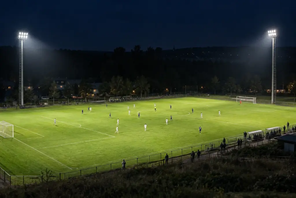 Lo stadio comunale illuminato di notte: quella luce uniforme che si diffonde sul manto erboso, proprio come previsto da un progetto di illuminazione sportiva completo.