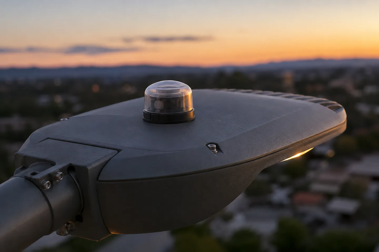 Grande plano da cúpula da fotocélula no topo de um moderno projetor de iluminação pública LED, o pequeno componente de controlo que determina a ativação do sistema do anoitecer ao amanhecer e que é o elemento principal da lista de verificação de manutenção da iluminação pública.