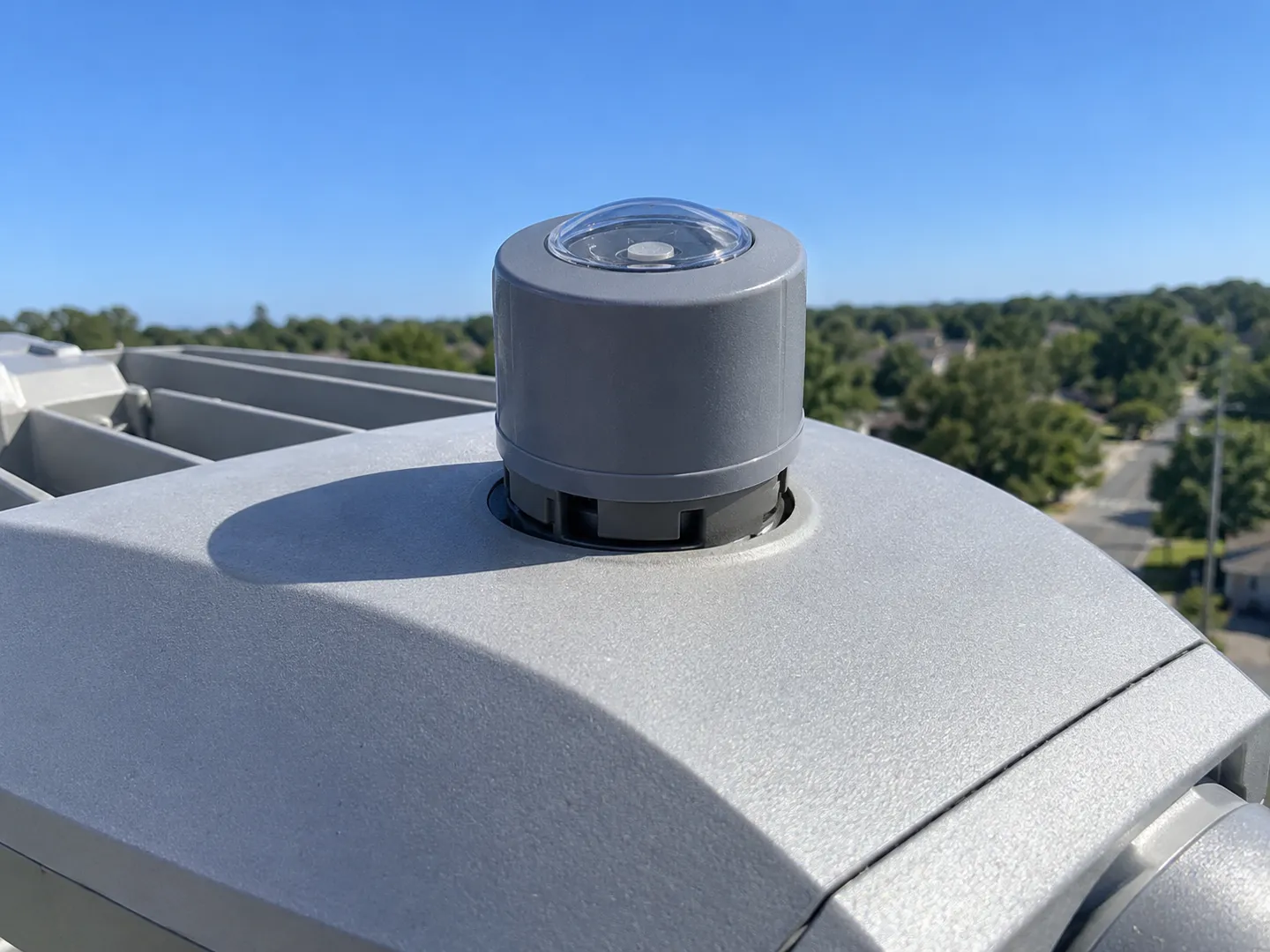 Una fotocélula con cierre giratorio alojada en su soporte en la parte superior del cabezal de una farola, la interfaz estandarizada que convierte al sensor de luz en una pieza sustituible